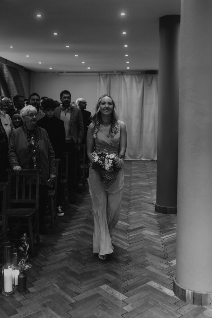 Bridesmaid Walking Down Isle in Wedding Ceremony at The Pumping House, Ollerton. Wedding Photographer