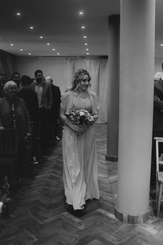 Bridesmaid Walking Down Isle in Wedding Ceremony at The Pumping House, Ollerton. Wedding Photographer