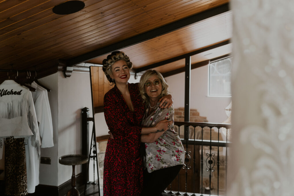 Alternative bride hugging her mum while getting ready in the morning at Willow Marsh Farm captured by a relaxed wedding photographer