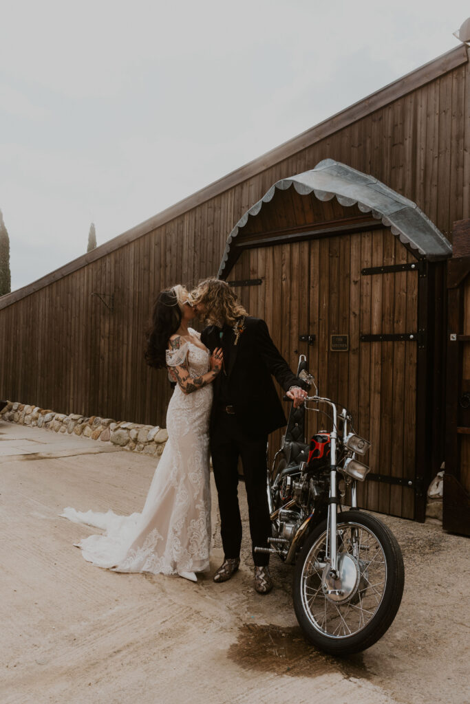 shot of a cool couple poses confidently next to a motorbike, epitomising their alternative and stylish approach to love and life at