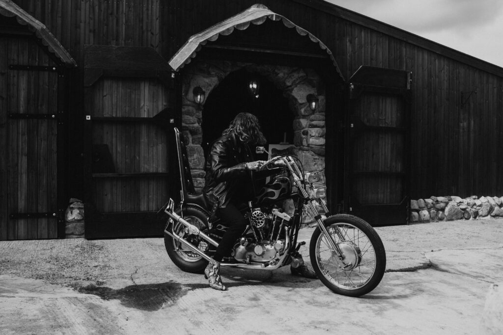 alternative groom arriving on his Harley Davidson  in black and white at willow marsh farm