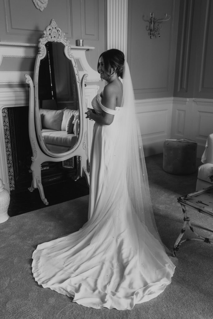 wedding black and white photo of bride getting ready with her finishing touches at davenport house 