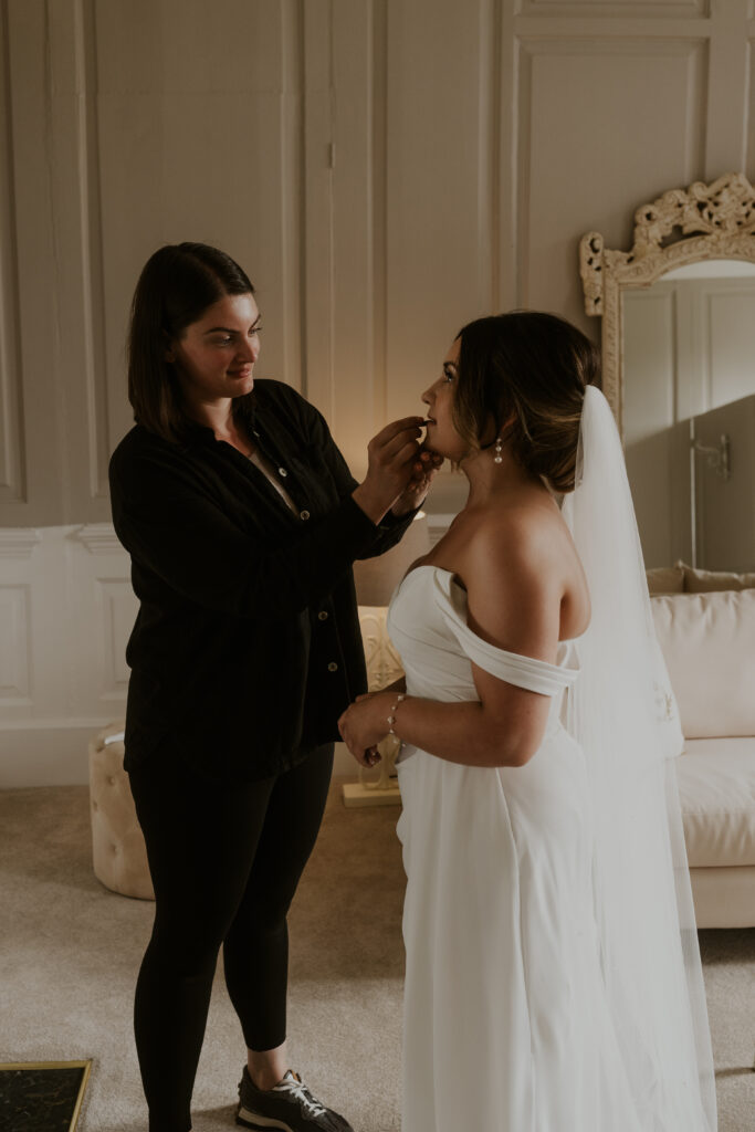wedding photo of bride getting ready with her finishing touches at davenport house 