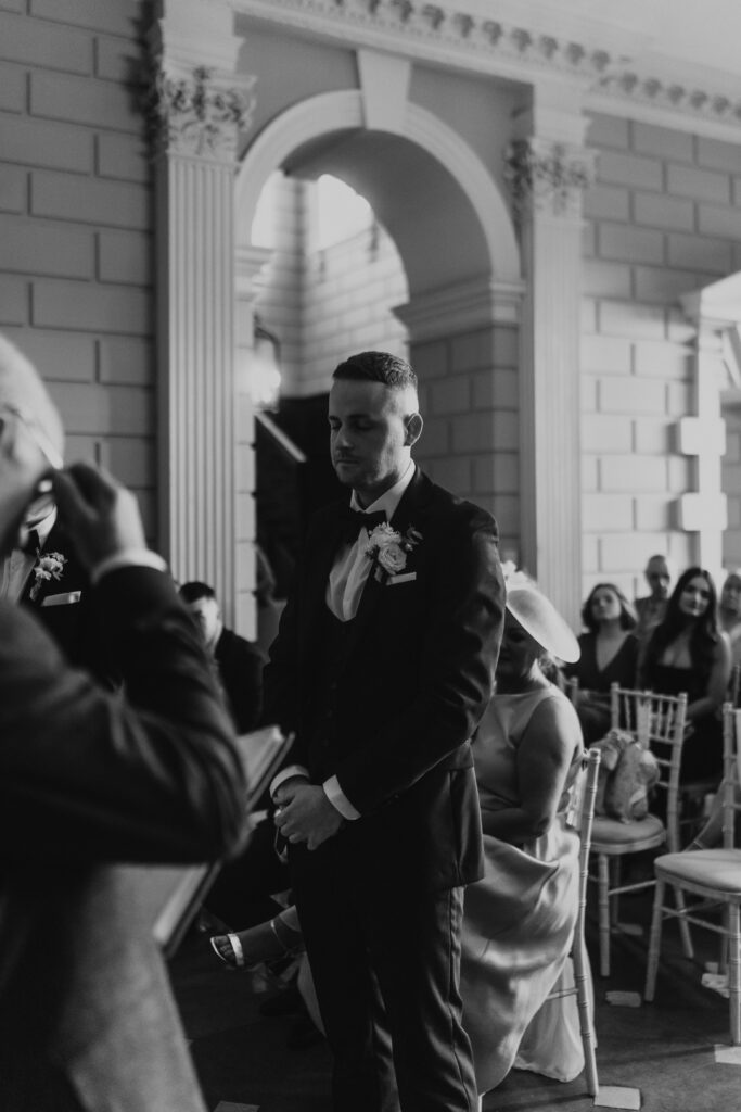 the groom waiting at the end of the isle for his bride at davenport house 