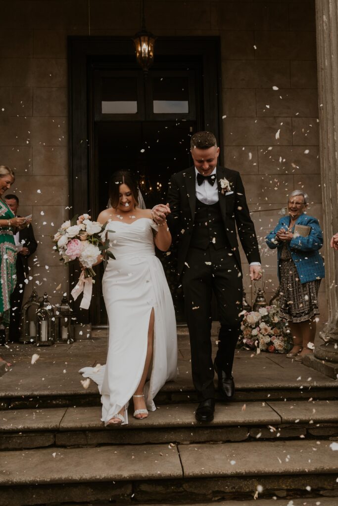 bride and groom laughing while walking through the confetti line at davenport house
