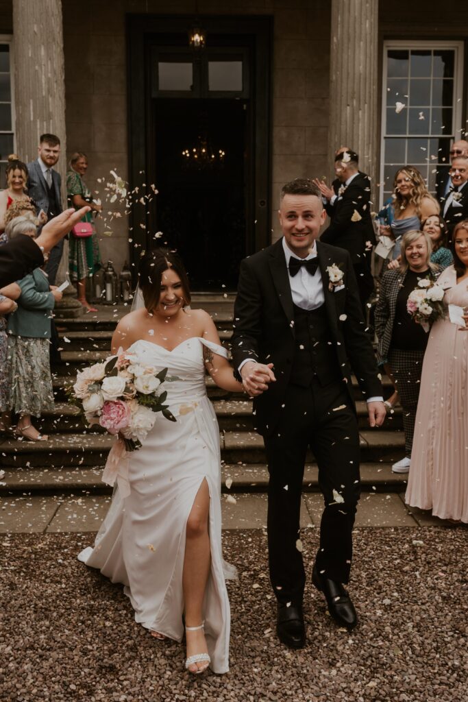 bride and groom laughing while walking through the confetti line at davenport house