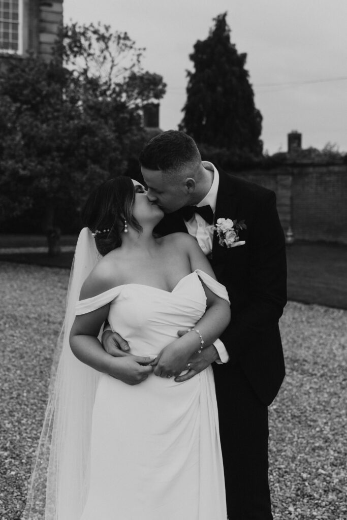 Black and White cinematic shot of newly married couple sharing a joyous and tender first kiss as husband and wife.