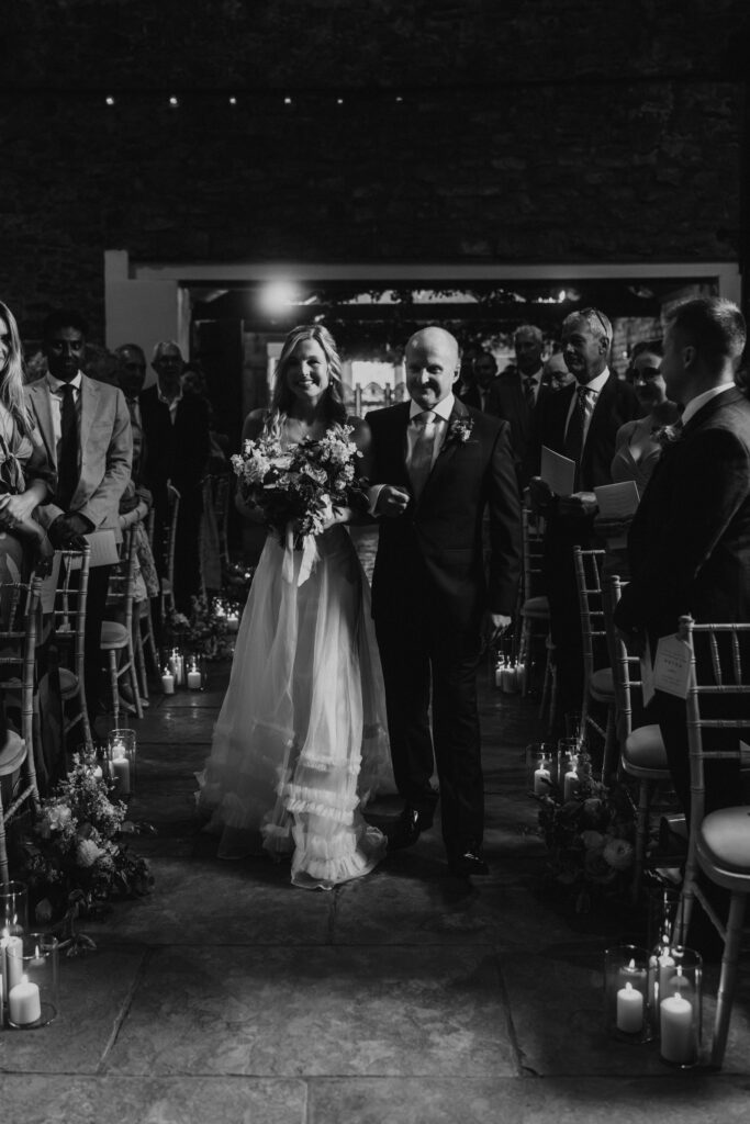The bride and her Dad in beautiful half penny london wedding dress walking down the isle at eden barn wedding venue