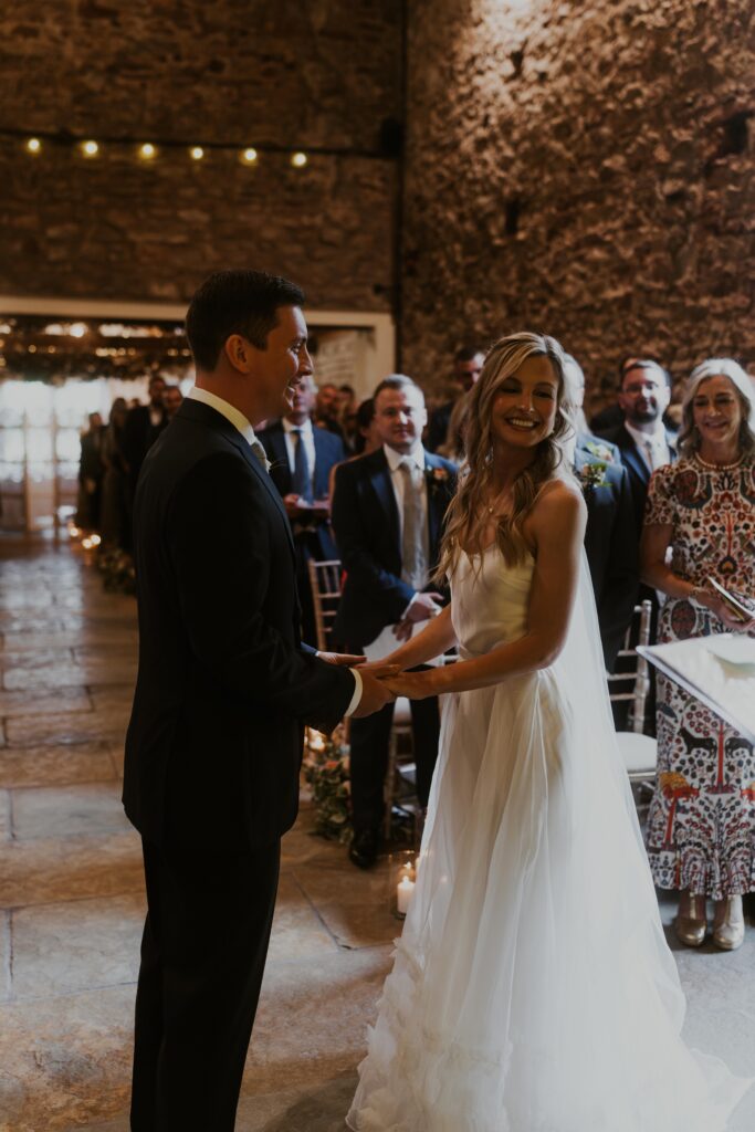 bride and groom laughing with each other as they exchange their marriage vows at Eden Barn Wedding venue