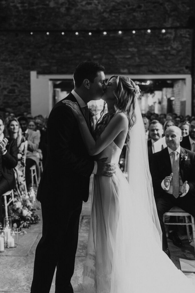 bride and groom share their first kiss in theit ceremony at Eden Barn Wedding venue