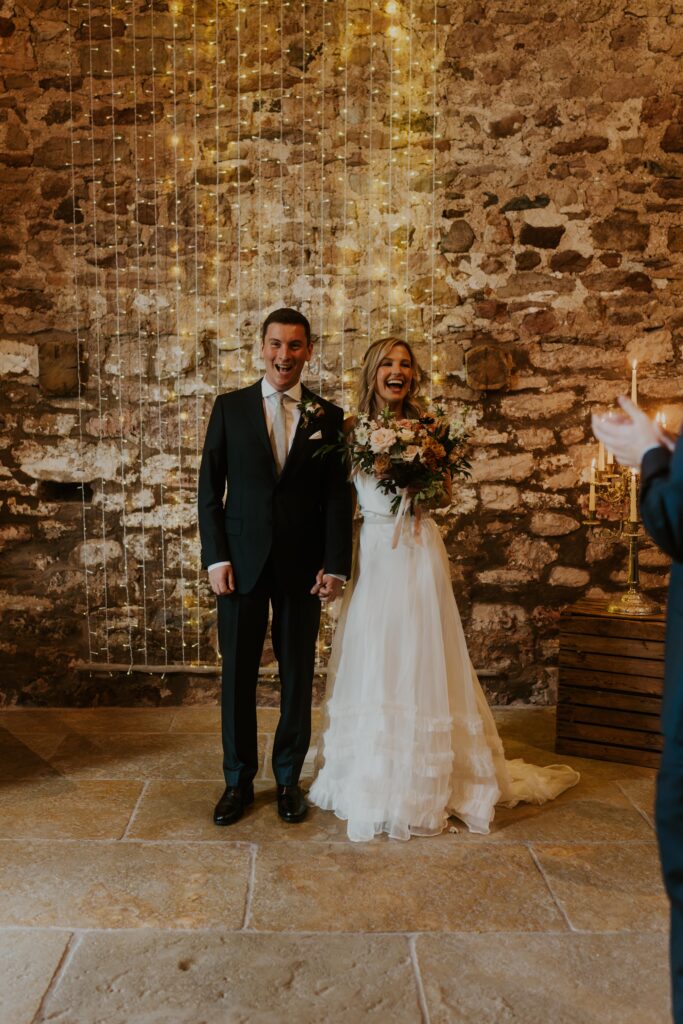 bride and groom exit their ceremony with beaming smiles at Eden Barn Wedding venue