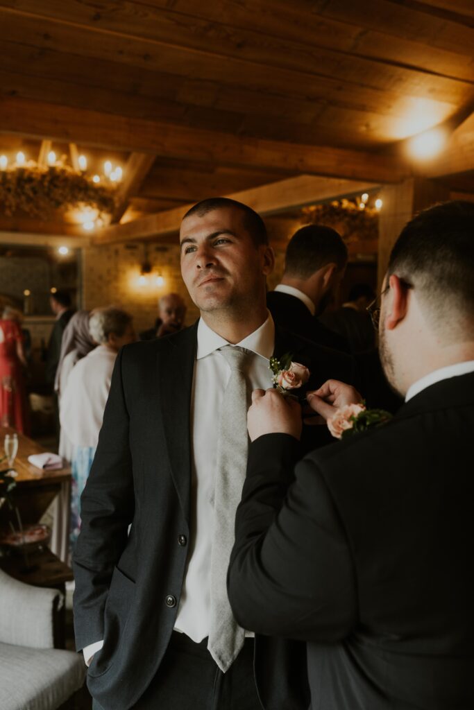 groom putting on button hole for his groomsmen at eden barn wedding venue