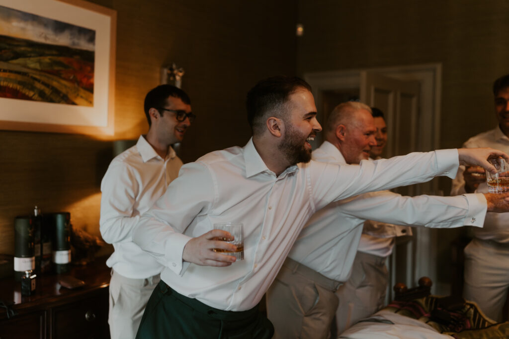Groom celebrating his wedding morning with his groomsmen with an alcoholic drink