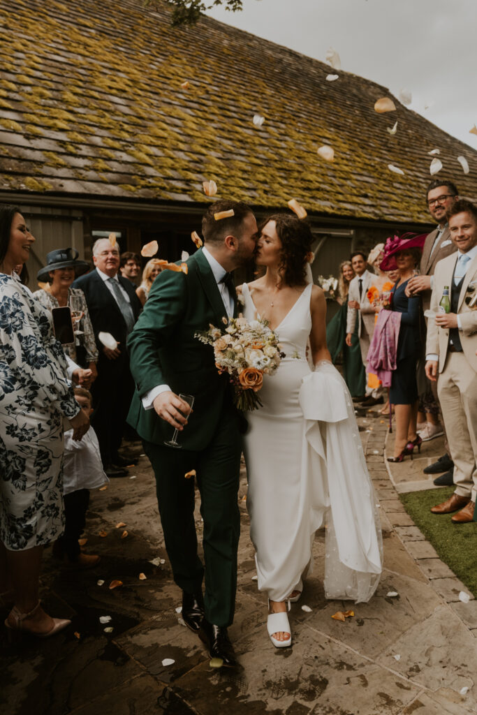 the bride and groom smiling and laughing as they walk down their confetti line at tithe barn wedding venue