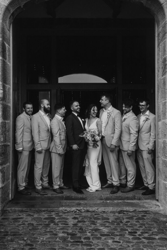 the group photos in the archway of tithe barn in black and white
