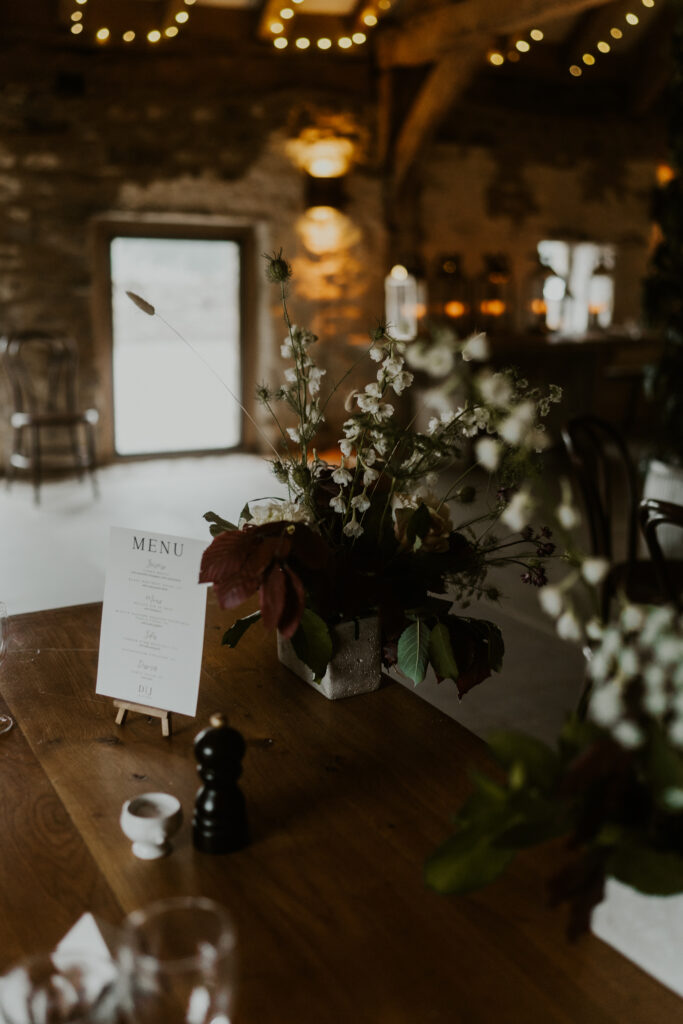 Tithe Barn wedding venue decor with green flowers and white signage 