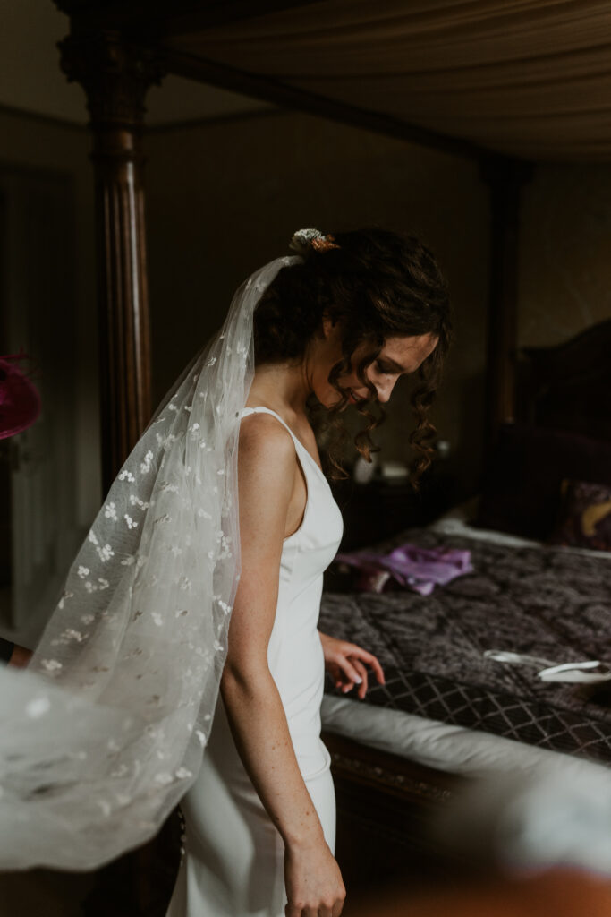 the bride getting into her white wedding gown ahead of her ceremony at tithe barn wedding venue